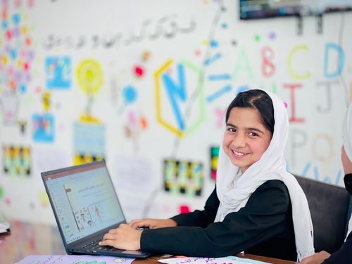 Smiling girl on a laptop at a school in Afghanistan