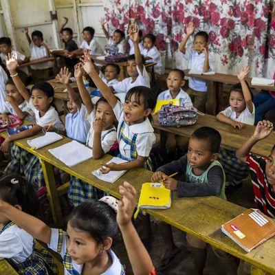 Children in a classroom in the Philippines raise their hands