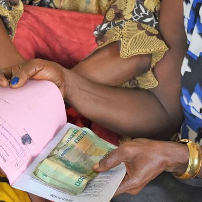 A woman holds a booklet and a small collection of cash during a meeting