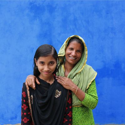 A mother and daughter in Bangladesh in front of blue wall.