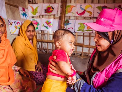 A community health worker in the Rohingya refugee camp holds a happy refugee baby