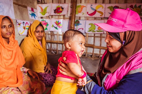 A community health worker in the Rohingya refugee camp holds a happy refugee baby