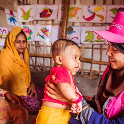 A community health worker in the Rohingya refugee camp holds a happy refugee baby
