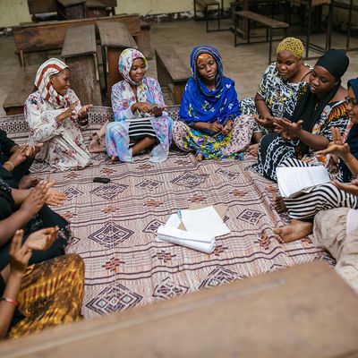 Women sitting on a rug together in colourful clothes