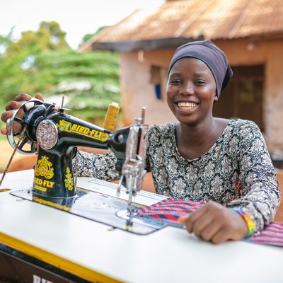 Girl smiling as she works with a sewing machine