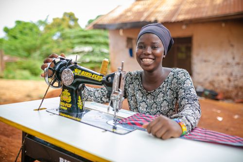 Girl smiling as she works with a sewing machine
