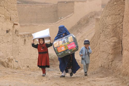 Family walking with young children carrying bags