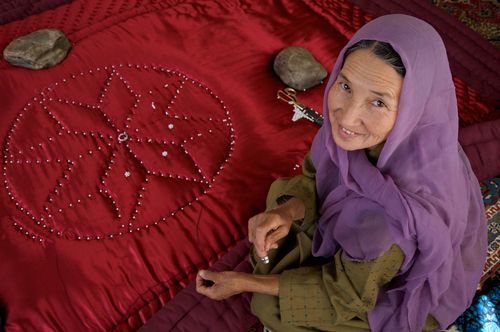 Smiling women in a purple headscarf sewing red fabric