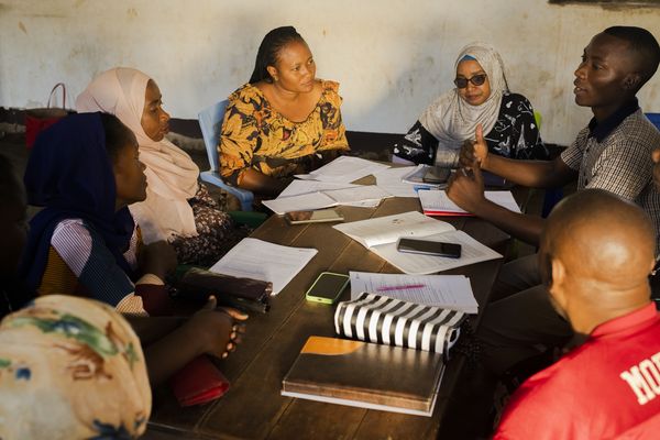 Group of people meeting and discussing papers at a table.