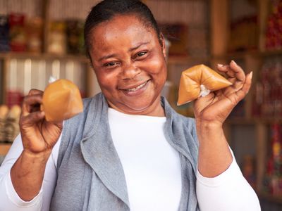 A Ghanian woman smiles at the camera while showing food items for sale