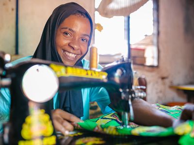 Woman smiling working on a sewing machine in Tanzania