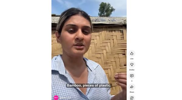 Sidra speaks about shelter contruction in front of a home made of mostly bamboo