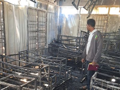 wreckage left after Cox's Bazaar fire, man stands in middle of burned out classroom