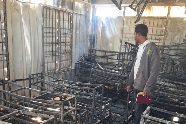 wreckage left after Cox's Bazaar fire, man stands in middle of burned out classroom