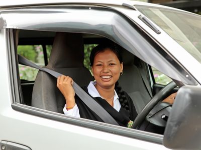 BRAC Bangladesh | A young women in black and white clothing behind the wheel smiling