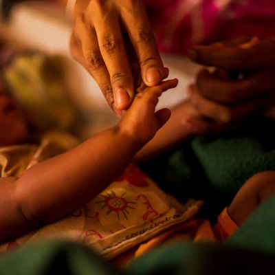 A young baby's hand is held gently by an adult.
