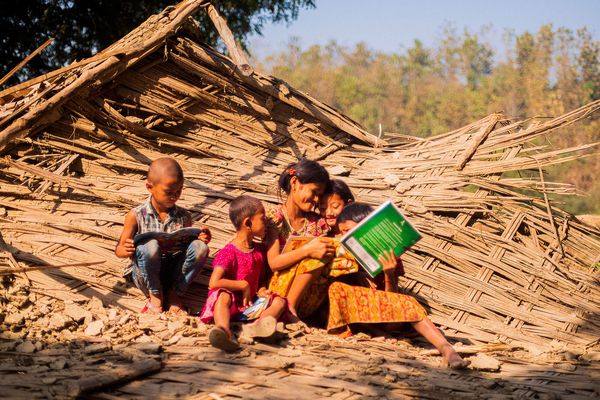 A woman smiles as she reads to four children.