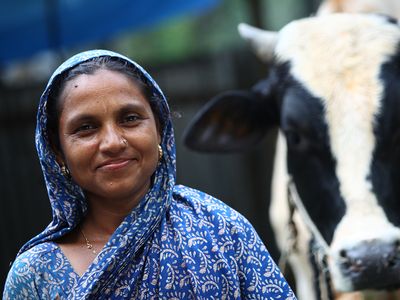 A woman in Bangladesh poses with her cow