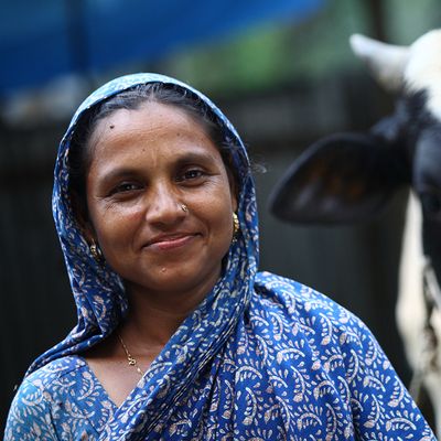 A woman in Bangladesh poses with her cow