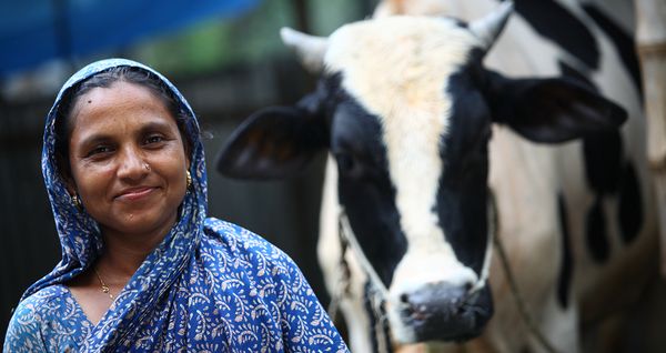 A woman in Bangladesh poses with her cow
