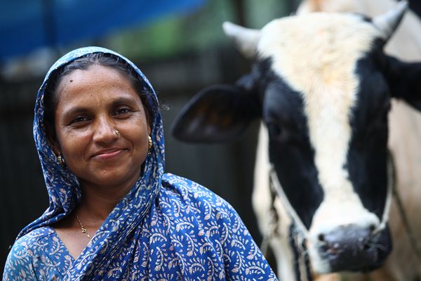A woman in Bangladesh poses with her cow