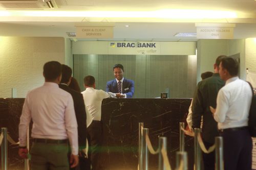 A group of people queue to talk to the BRAC Bank teller at the counter