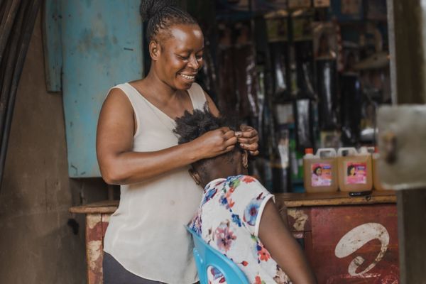 BRAC Uganda, AIM, Nongo Natasha braiding hair at her beauty salon