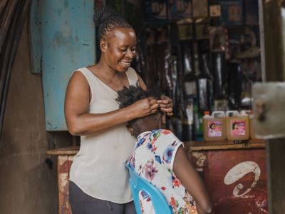 BRAC Uganda, AIM, Nongo Natasha braiding hair at her beauty salon