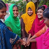 Five girls stand in a semi-circle holding hands.