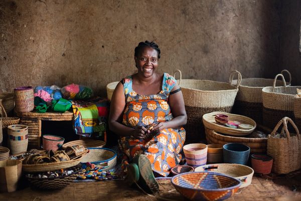 A microfinance client smiles as she sits amid her wares
