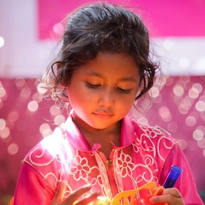 A young Rohingya girl looks down at a colorful toy