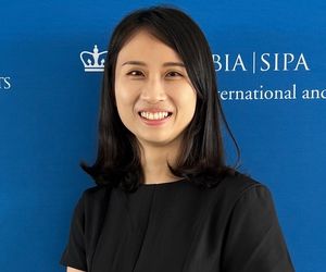 An Asian woman wearing a black tshirt smiles at the camera.